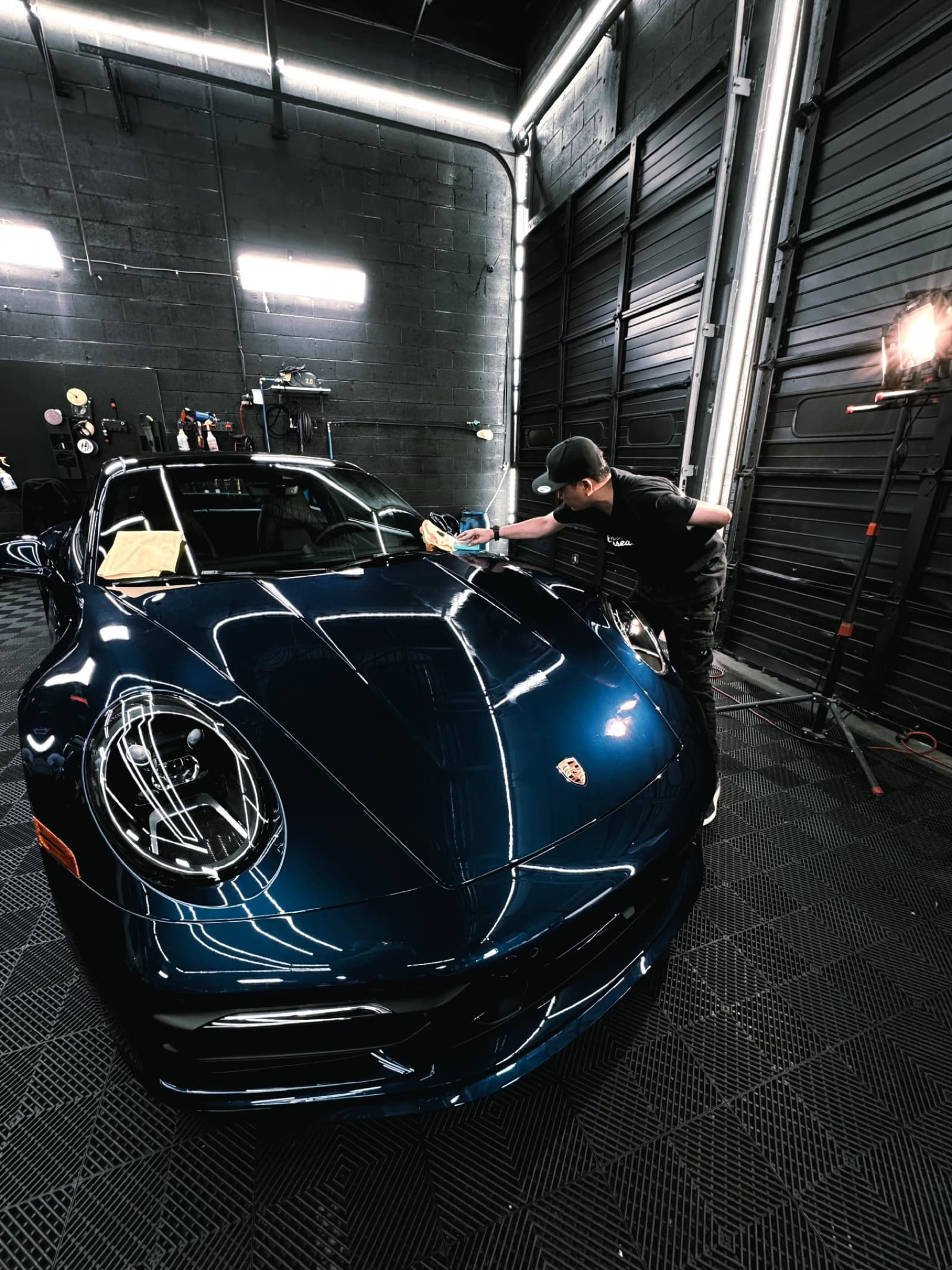 Detailer polishing a Porsche 911 inside the A1 Wrap shop
